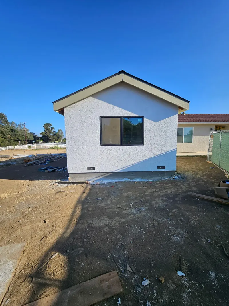 Gable end of the stucco ADU with a black-framed window