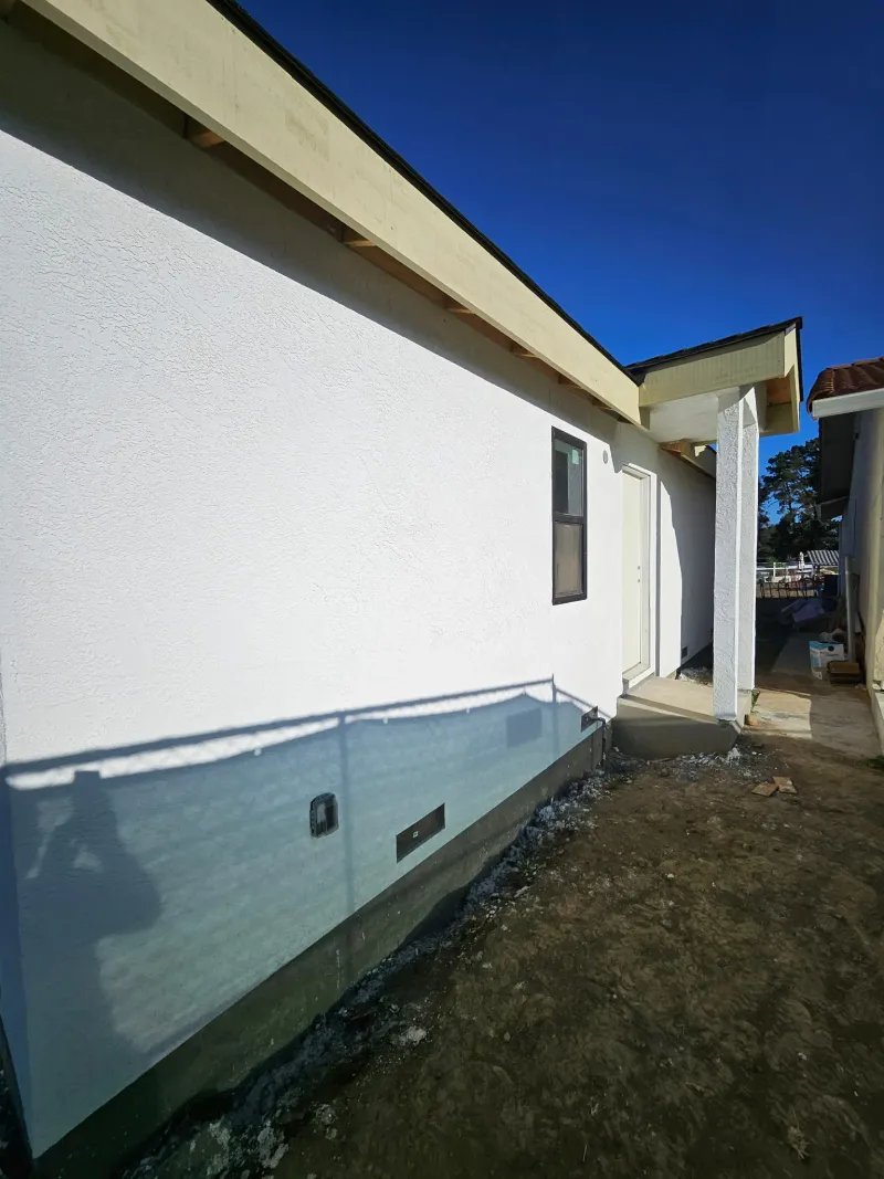 Side wall of the ADU in fresh stucco, looking toward the entry
