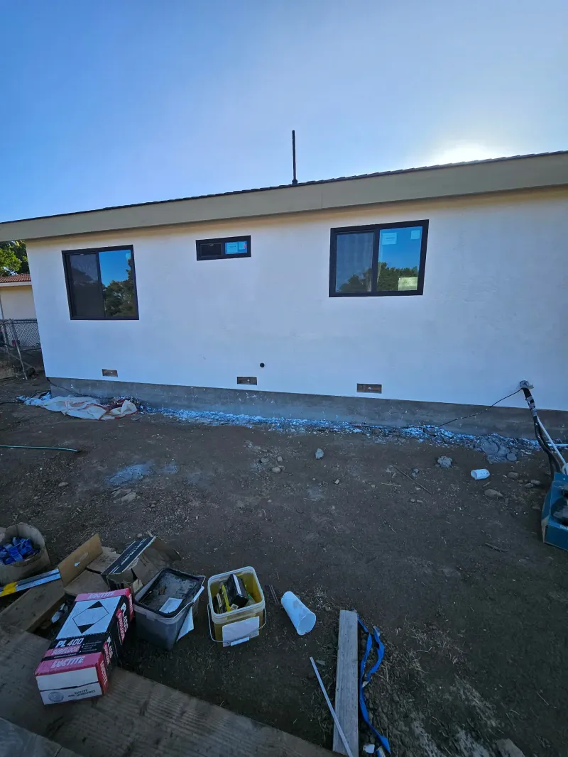 Long wall of the ADU with three black-framed windows in finished stucco